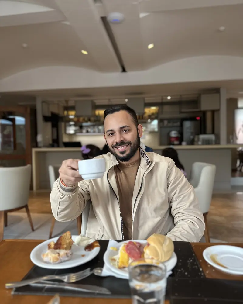 Alan Soares sorrindo, tomando café