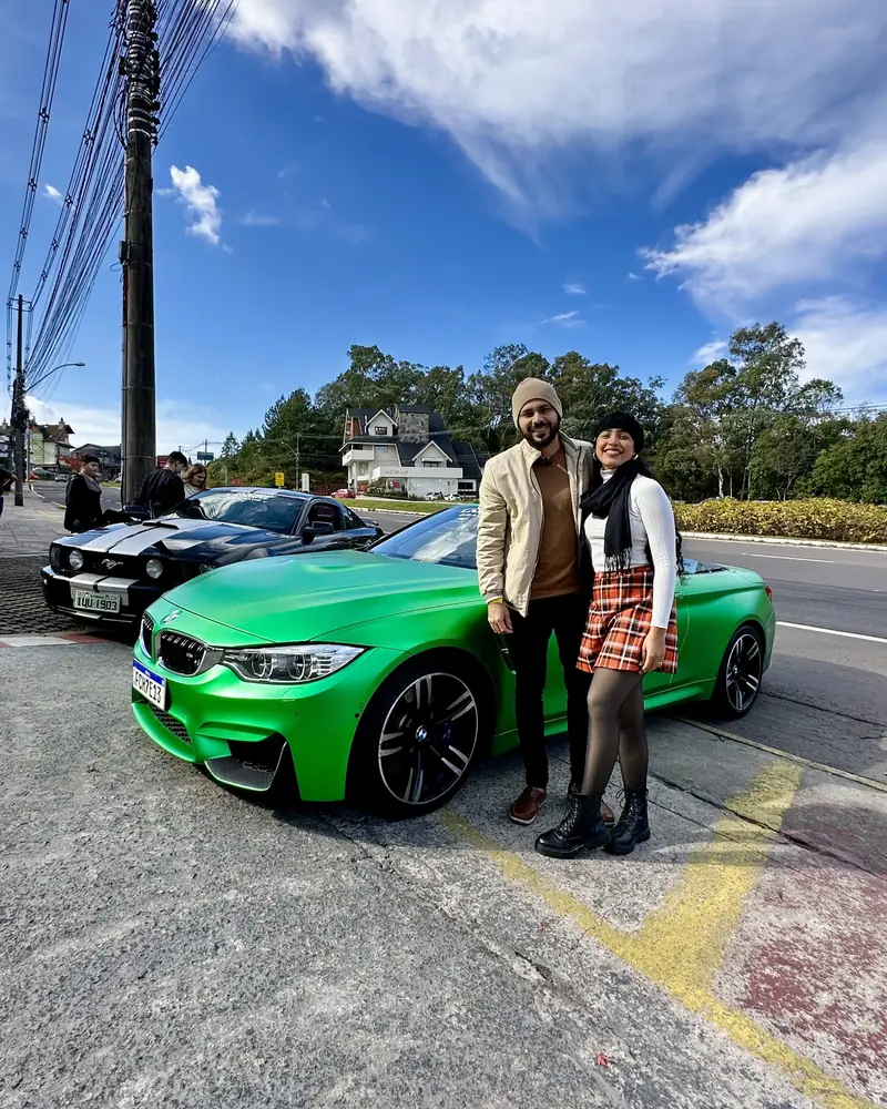 Alan e a esposa ao lado de um carro verde