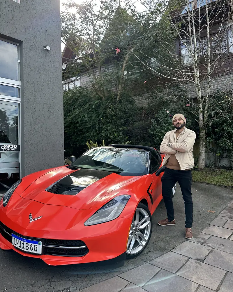 Alan ao lado de um Corvette vermelho